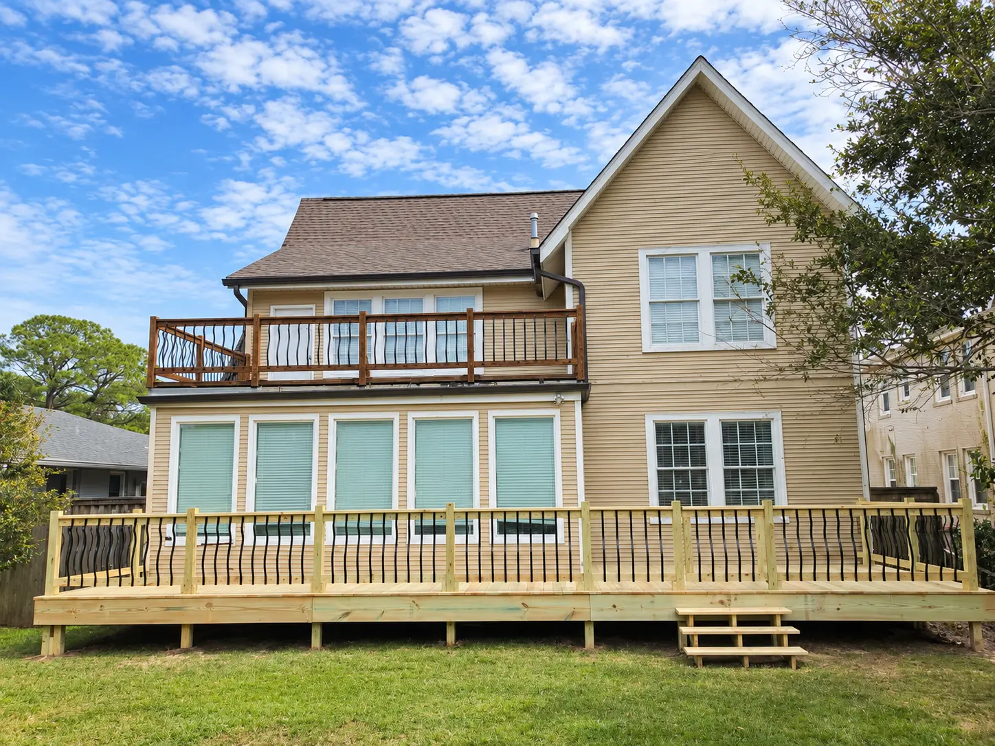 Completed lower deck with curved railings behind the home