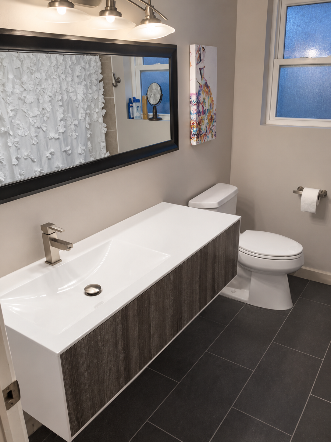 Finished bathroom with floating vanity, framed mirror, and new fixtures